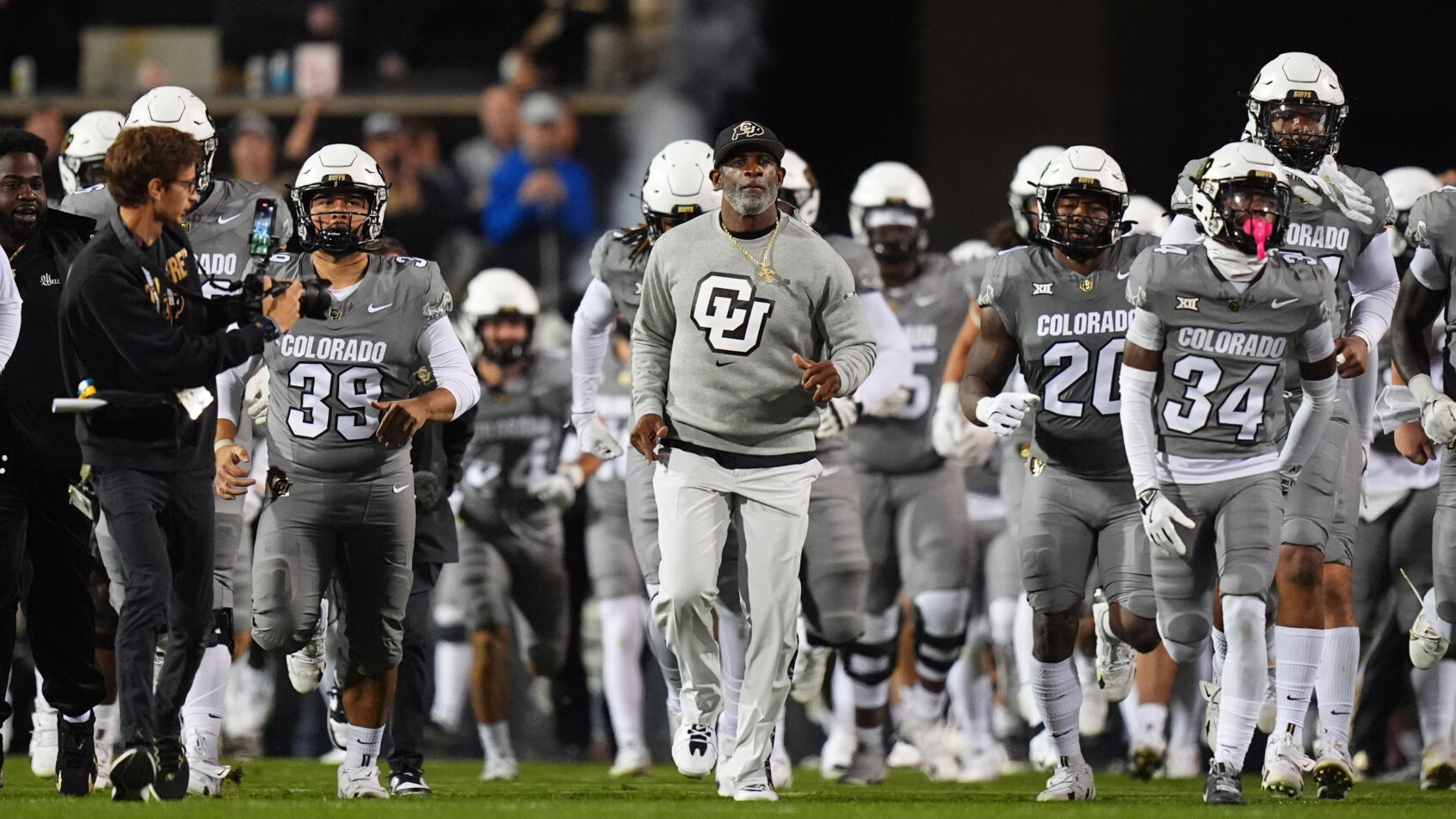 Football team enters field in gray uniforms