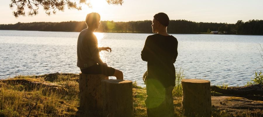 Two individuals conversing lakeside